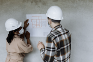 Construction professionals reviewing architectural plans on site wearing safety helmets