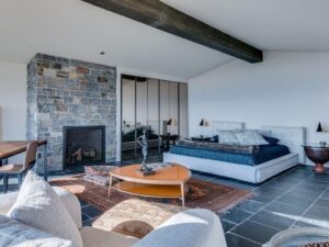 North Shore MA modern bedroom remodel with stone fireplace, exposed beam, and custom interior design